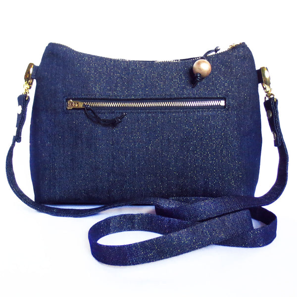 the back of the calliope crossbody bag is dark denim accented with gold metallic threads, and features a 7" zippered pocket