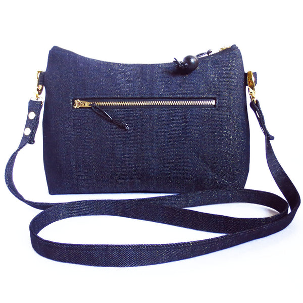 the back of the raina crossbody bag is dark blue metallic denim with a 7" zipper pocket