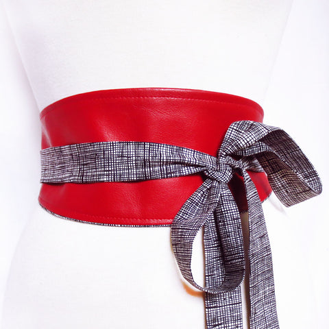 Obi style wrap belt in red vinyl with long ties in black and white crosshatch print, tied in a loose bow off to one side