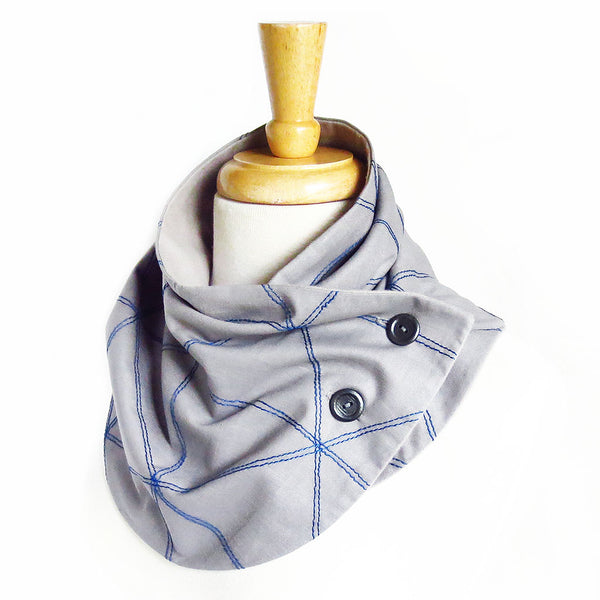 Fabric button scarf with triangle motif stitched in purple thread on light gray cotton. Lined in light gray flannel with two hand painted buttons.