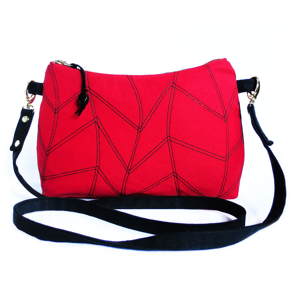 red and black denim crossbody bag with chevron wave motif stitched on front. 