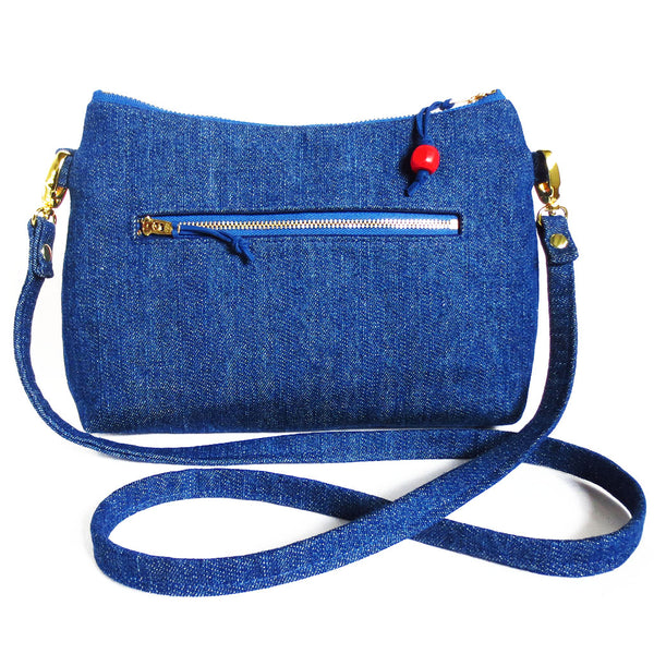 the back of the persephone crossbody bag is dark blue denim with a 7" zipper pocket