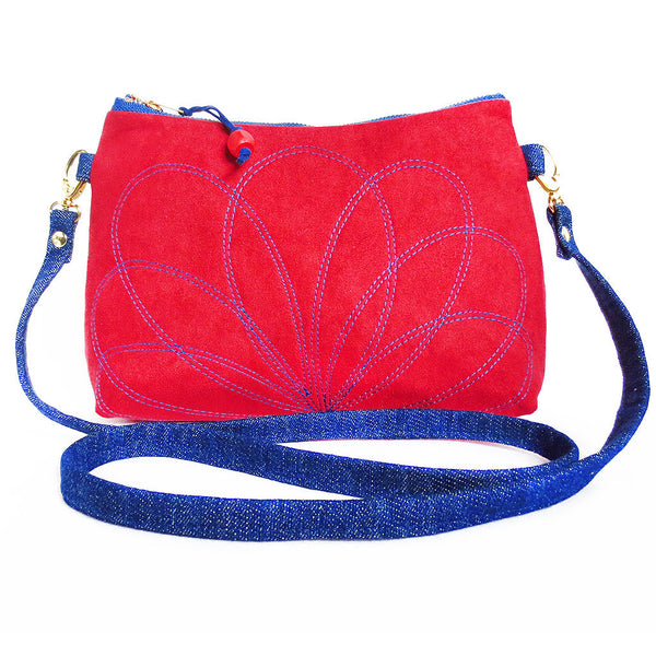 crossbody bag in red ultrasuede and dark blue denim, with a stitched floral motif on the front