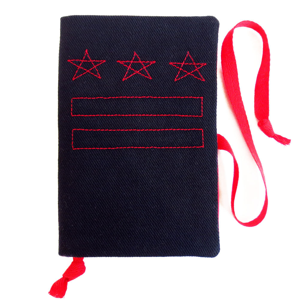 black canvas field notes cover, stitched with the DC flag in red thread, with red fabric book mark and wrap tie