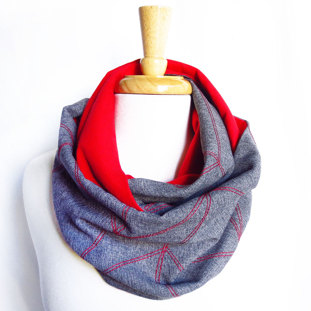 the cassandra infinity scarf is gray with a red chevron wave motif stitched in red, and is lined with red flannel