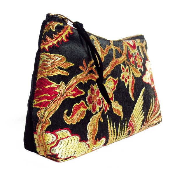 side view of zip pouch with gold and red damask paired with black denim 