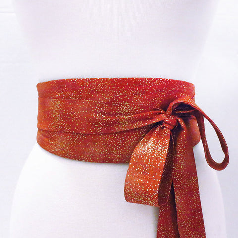 Josephine belt wrapped to show the printed side, tiny gold dots scattered on a warm red background. Long ties are tied in a large loose bow to one side.